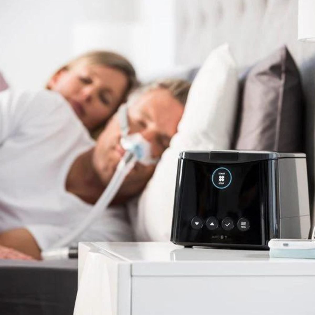 SleepStyle Auto CPAP Machine on bedside table being used by man | IntusHealthcare.com
