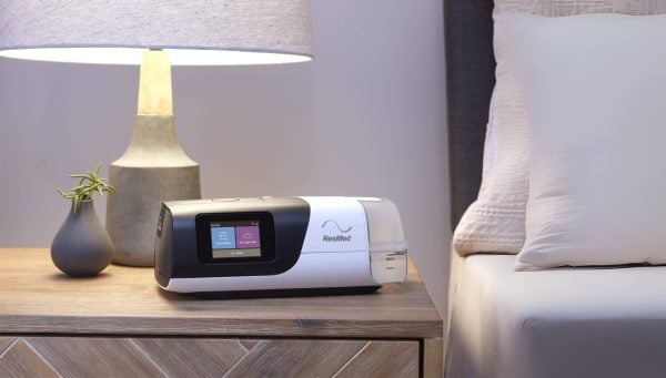 ResMed AirSense 11 Auto CPAP Machine on bedside table next to lamp | Intus Healthcare