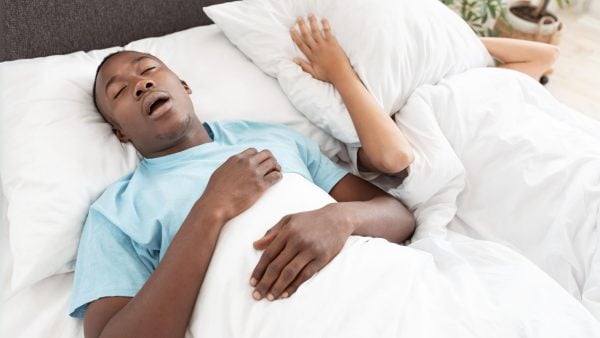 Man snoring in bed, woman covering head with a pillow | Intus Healthcare
