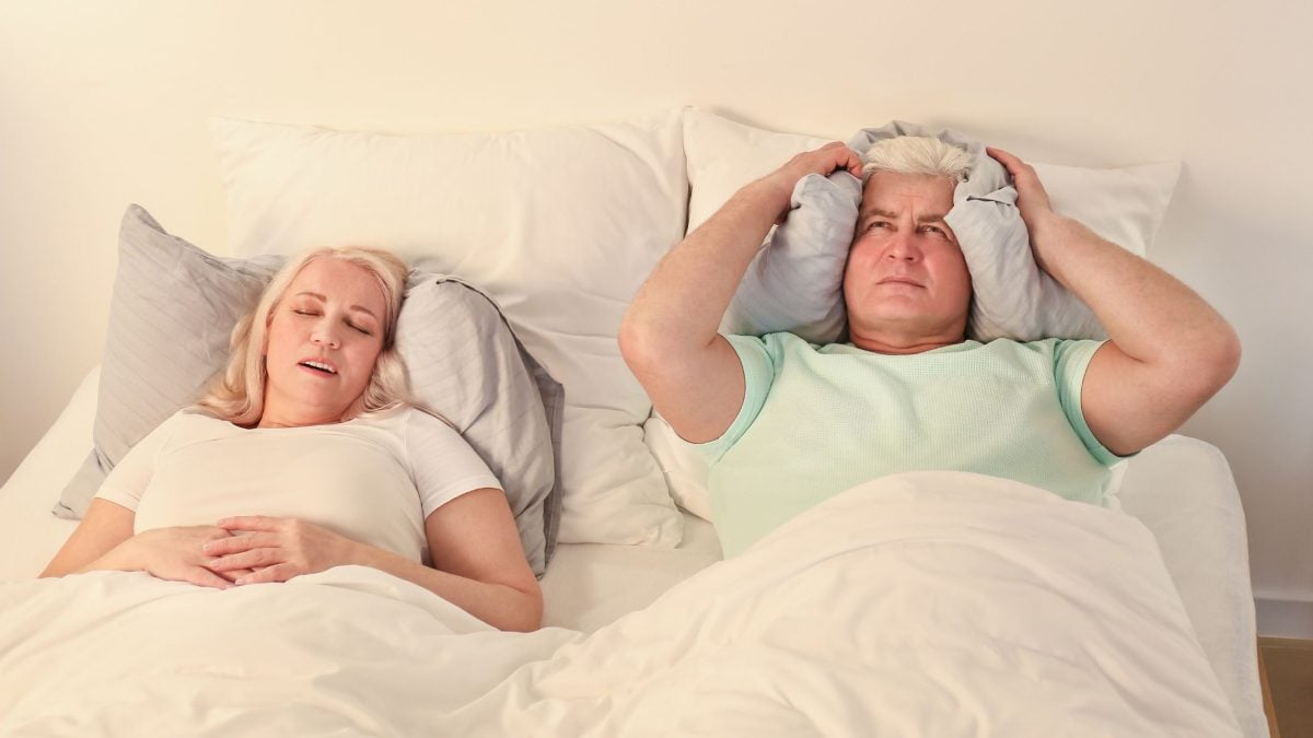 Woman snoring in bed, husband covering ears | Intus Healthcare