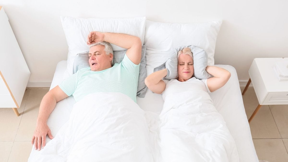 Husband snoring loudly in bed, wife covering ears with a pillow | Intus Healthcare