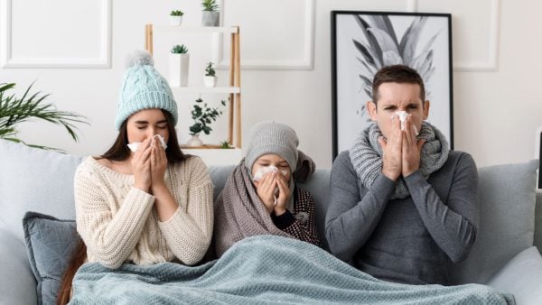 Mum, dad and child sat on sofa blowing their noses due to a cold | Intus Healthcare